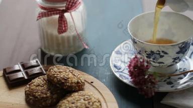 壶中红茶的配制.. 用茶托将热茶倒入白色陶瓷杯中。 木制桌子、饼干、糖