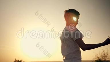 一个孩子正在日落时玩玩具飞机。 一个男孩拿着玩具的<strong>剪影</strong>，手拿着一架小飞机。 这就是