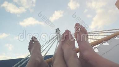 在年轻夫妇的双脚上，在吊床上休息，在天空背景下的slwomotion。 1920x1080。 高清高清
