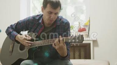 一个人演奏的吉他。 男子演奏声吉他慢动作视频。 在房间里，坐在生活方式的沙发上