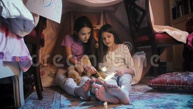 两个穿睡衣的女孩晚上在地板上读故事