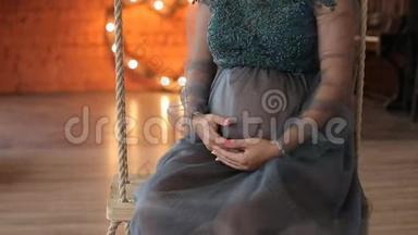 孕妇坐在装饰的秋千上。 家庭观念。 生育观念。