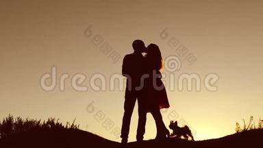 情侣在爱情里亲吻走日落的剪影自然慢动作视频.. 男人和女人的爱情轮廓与一个