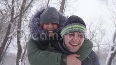 可爱的年轻人在雪地里的树林里快乐地背着<strong>女友</strong>