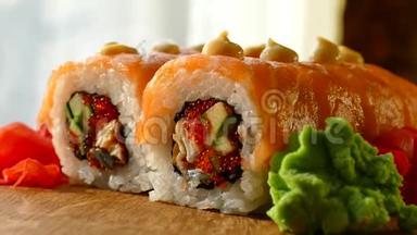 美味可口的寿司。 寿司配三文鱼片和新鲜黄瓜。 木头上有红姜和青芥末