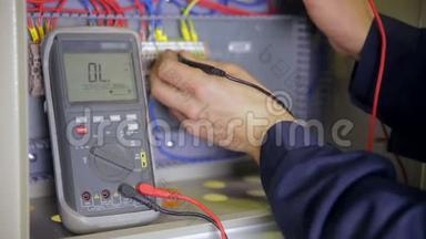 电工测试电力。工业工厂电工用万用表在电器上测试电压