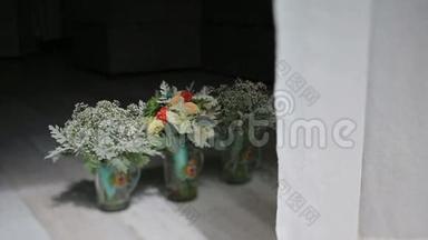 三个漂亮的结婚花束放在玻璃花瓶里，就在窗帘旁边的地板上