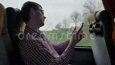 年轻人在长途旅行中，在上下班途中通过公共汽车查看电子邮件。 使用手机的特写。