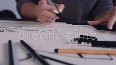 女人坐在办公室的桌子旁，拿着铅笔，在纸上<strong>画出</strong>鞋子的草<strong>图</strong>。
