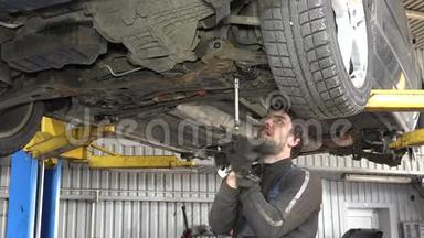 男式汽车修理工，带扳手，在车库下工作