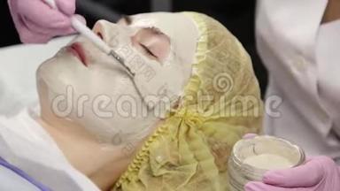 美容师把面膜敷在问题皮肤上。 清洗皮肤的年轻妇女