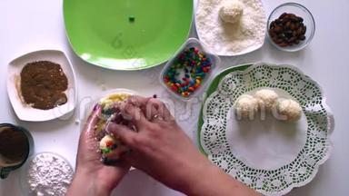 女人用炼乳、椰子刨花和杏仁准备糖果。 用彩釉装饰糖果.