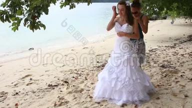 助理协助新娘在沙滩上系<strong>婚纱礼服</strong>