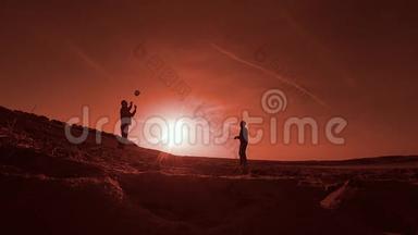 排球。 两名男子在夕阳下沙滩上打排球剪影