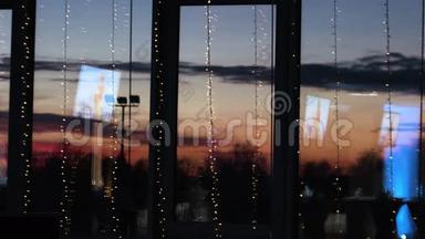 蓝色电视屏幕反射在装饰的大窗户上。 美丽的<strong>红日</strong>落在玻璃后面。
