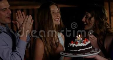 一群微笑的朋友在酒吧里吹蜡烛庆祝生日