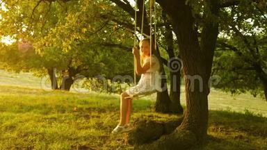 孩子在公园里荡秋千。 年轻女孩在橡木树枝上的绳索秋千上摆动。 少女喜欢在秋千上飞行
