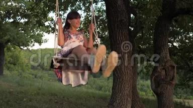 <strong>孩子</strong>们在公园的秋千上<strong>晒太阳</strong>。 年轻女孩在橡木树枝上的绳子上摆动。 少女喜欢飞行