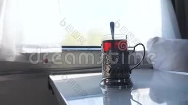 铁路旅行概念。 一杯玻璃杯中装有勺子的茶，一个老式的站在<strong>火车车厢</strong>的桌子上