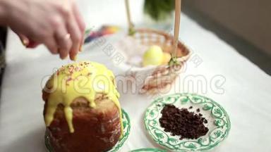 复活节蛋糕上有黄色的糖霜和五颜六色的花洒在白色的桌子上。 女孩甜蜜的谷物洒复活节蛋糕