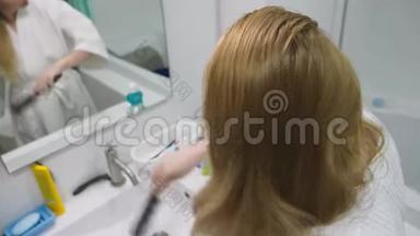 发健康，脱发理念.. 女人在浴室里梳着她那金发受损的干头发