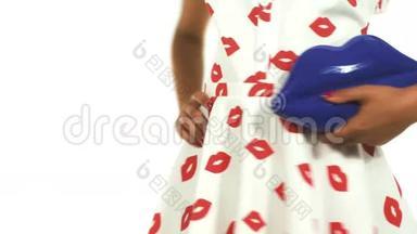 模特拿蓝色手袋在嘴唇形状。 在白色背景的工作室里穿着一件衬裙的模特。
