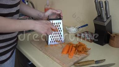 女手篦橙胡萝卜与碎纸机工具在厨房。 4K