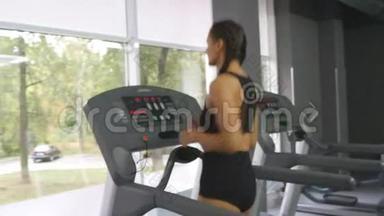年轻强壮的女人，有着完美的健身身材，穿着运动服，在健身房跑步机上跑步。 女子有氧运动