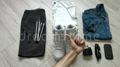 男士`休闲服装包括深蓝色短裤，白色衬衫，牛仔衬衫，白色运动鞋和配饰。 平躺，顶部