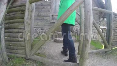 穿绿色外套的女孩打开木门，爬上石阶。 4K