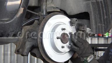 工人安装新的制动盘在旧汽车上提升在修理车间。