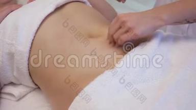 一位年轻女子在一家美容院做抗<strong>纤维素</strong>腹部按摩。 按摩师为年轻人做脂肪团按摩