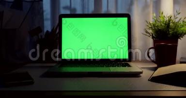 带有绿色屏幕的笔记本电脑。 黑暗的办公室。 多利加入。 完美地放置你自己的图像或视频。 正在使用的技术绿色屏幕。 <strong>语文</strong>