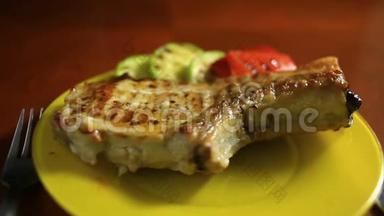 烤架上烤制的骨头上的小<strong>切口</strong>的特写。 烤肉放在盘子里，放着烤蔬菜。 热，蒸汽