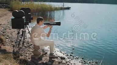 电影导演用两个相机在湖岸的扬声器上吃葡萄