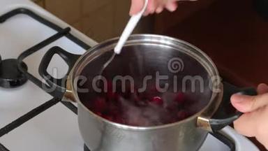 一个人把一勺<strong>冰冻</strong>的蔓越莓拌在平底锅里。 为棉花糖准备土豆泥。