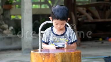 亚洲男孩在智能手机上玩游戏快乐，亚洲男孩庆祝在智能手机上赢得游戏。