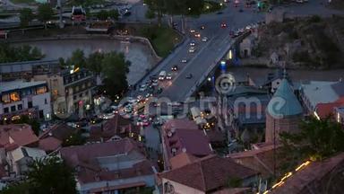 摄像机从上面聚焦到夜晚古老的欧洲城市景色。 道路上有发光前灯的汽车的运动