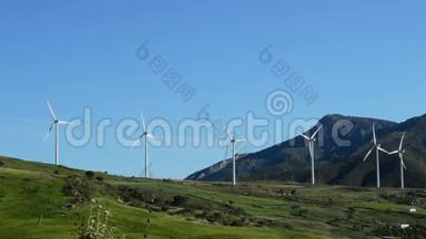 风力涡轮机在阳光明媚的日子里，能量在田野、道路和山脉一起移动