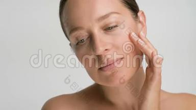 年轻女子皮肤光滑健康的特写美女肖像，她用手指轻轻地抚摸着她的脸