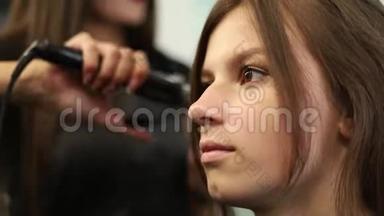 一个女<strong>人</strong>在发廊把头发弄直的特写镜头。 慢动作射击。 高清高清