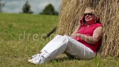 女人坐在干草堆附近，通过手机<strong>交流</strong>