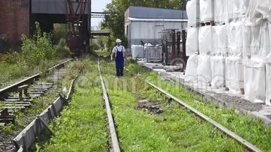 铁路工人戴着白盔沿着铁路行走