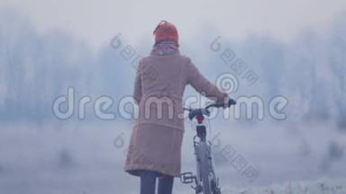 骑自行车穿过田野的年轻女子。黎明时分在田野里骑自行车的女人。