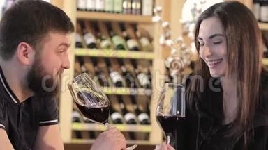 一个女孩和一个餐馆里的男人交流并喝红酒，一对年轻夫妇在一张桌子上喝红酒。