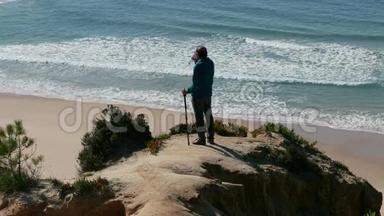人站在海洋上方的悬崖上，喝着瓶子里的水