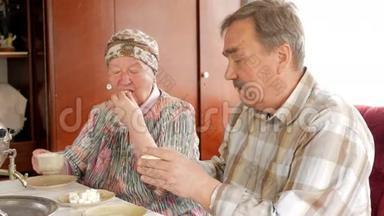 一对老夫妇正在喝一杯老式俄罗斯水壶萨莫瓦尔的茶。 一个留胡子的男人和他妻子在