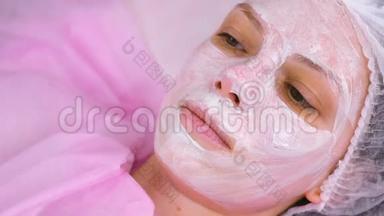 女人脸上带保湿面膜的美容程序。 面的特写..