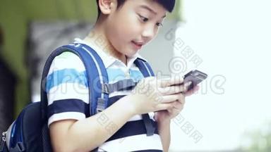 带背包的亚洲儿童使用数码手机