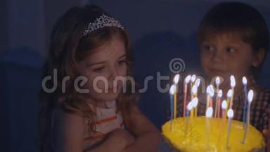 一个小女孩看着节日蛋糕上的蜡烛，慢慢地许愿